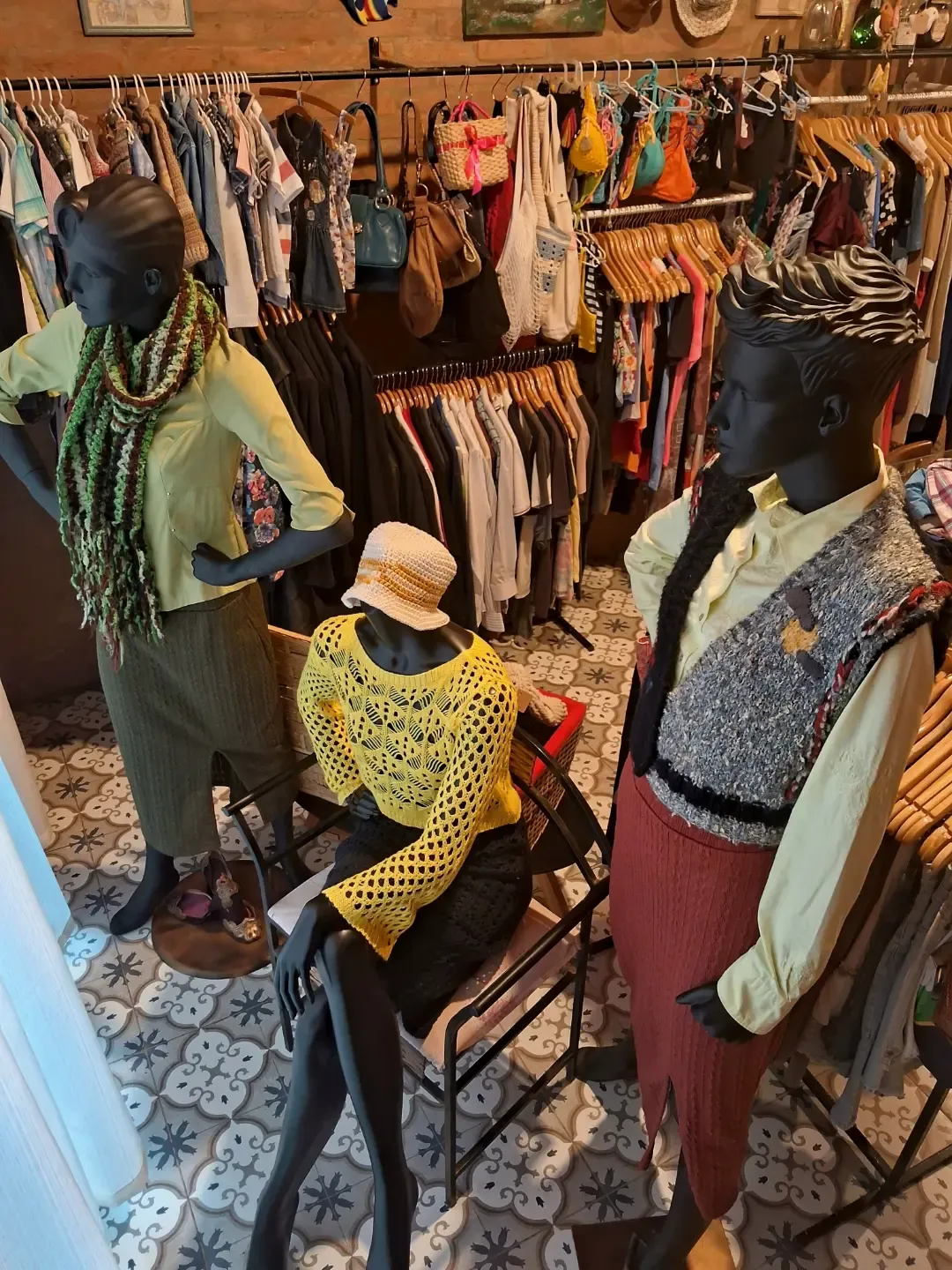 Manequins com tricô e crochê entre araras de roupas